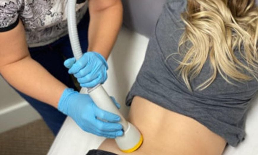 Female patient receiving SoftWave therapy on lower back area during clinical session – SoftWave-trt-marketing in action for patient care promotion.