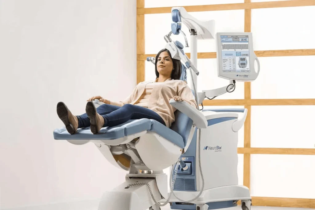 Patient seated on a TMS therapy machine during a treatment session – showcasing advanced care in TMS marketing strategy.